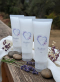 Multiple small tubes of hand cream on a wooden surface with a blurred natural background